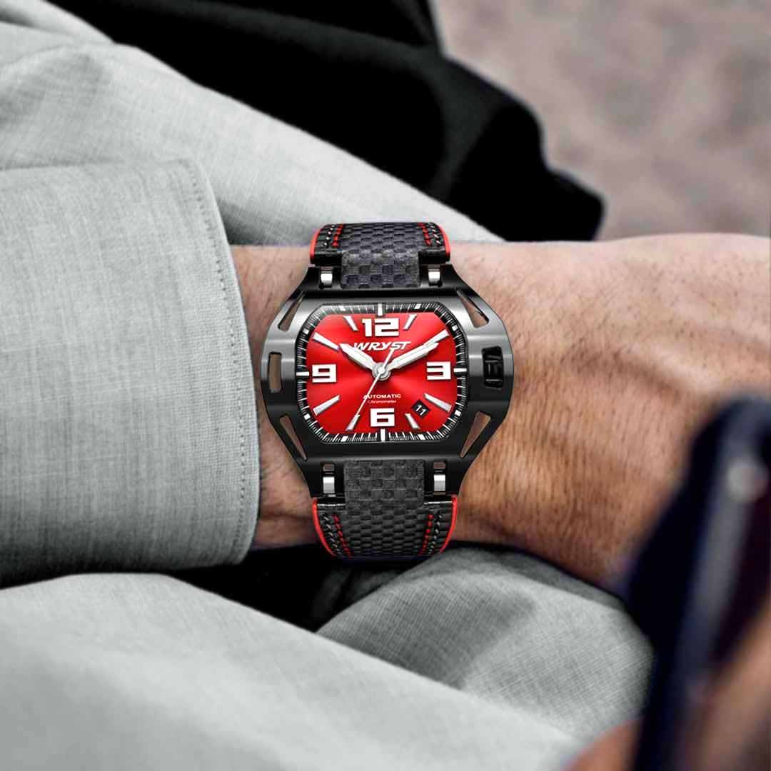 red automatic watch with black carbon fiber strap on a persons wrist